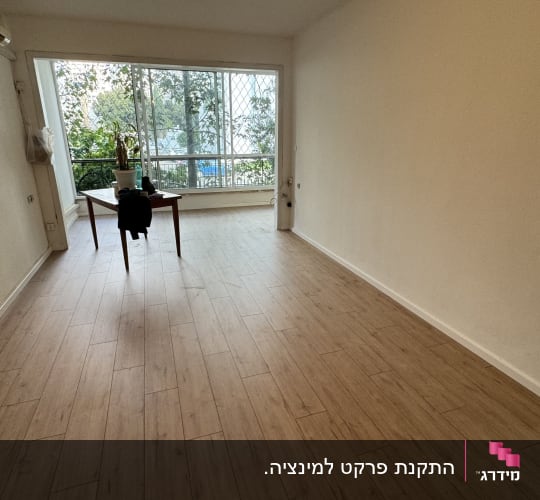 רצפת פרקט עץ בהירה בחדר ריק עם חלון גדול